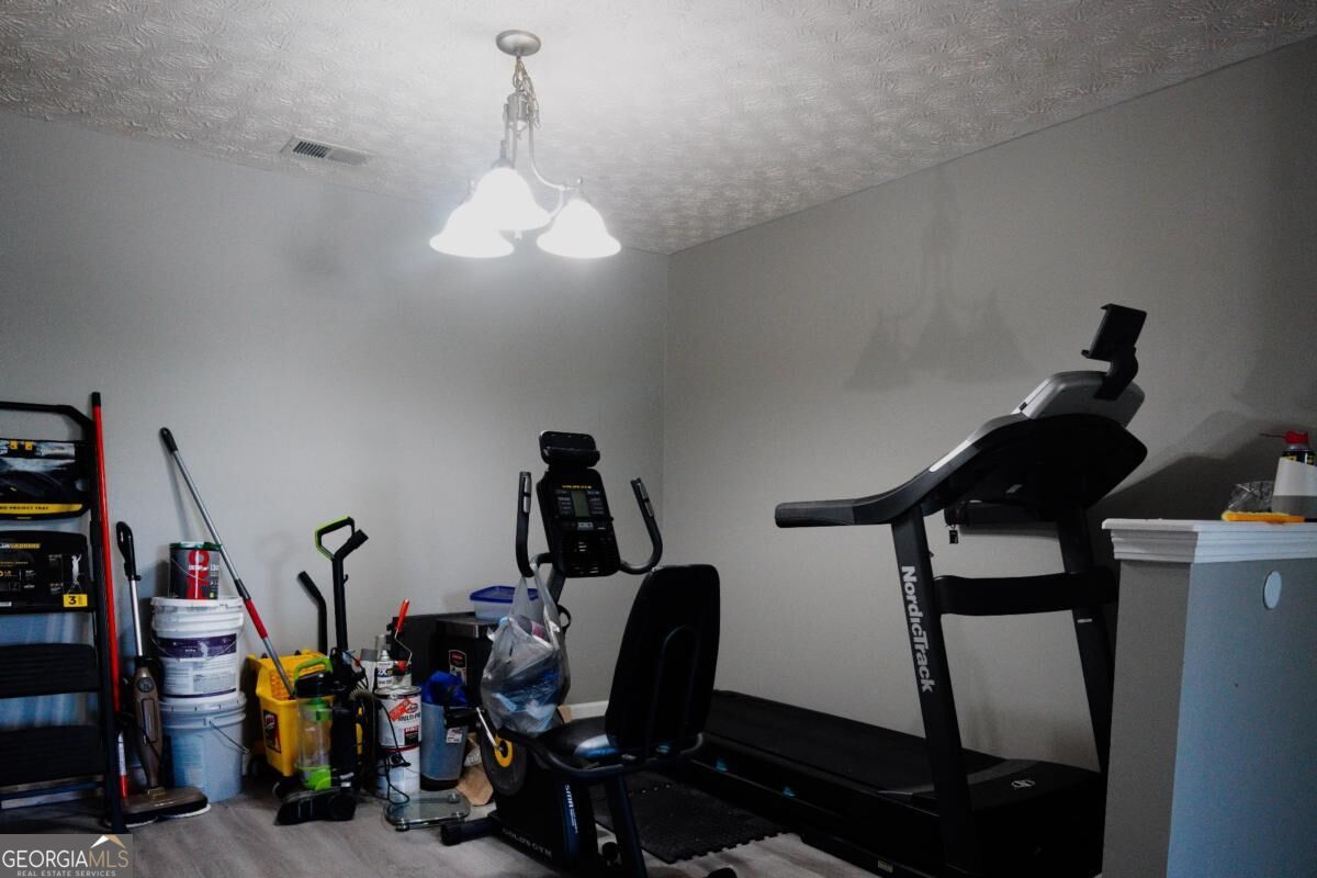Home gym with a NordicTrack treadmill, elliptical, and stored paint cans and tools.