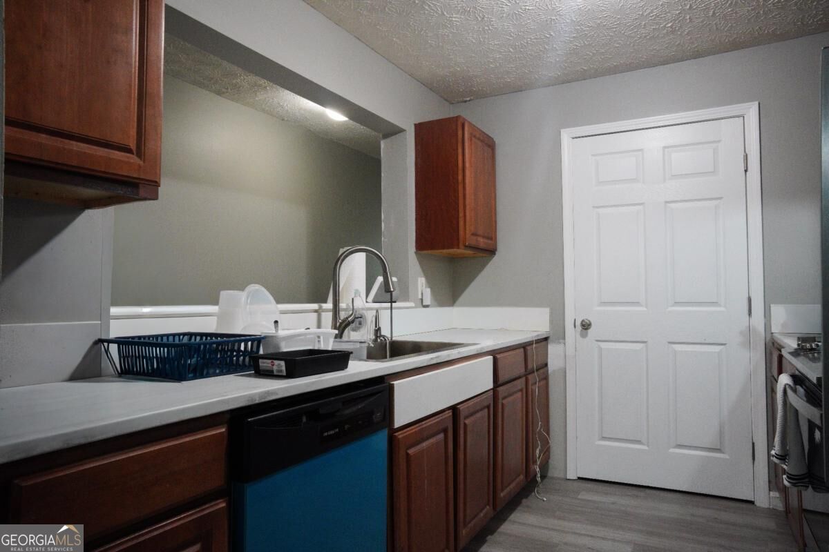 Kitchen with reddish-brown cabinets, a farmhouse-style sink, and a blue-front dishwasher.