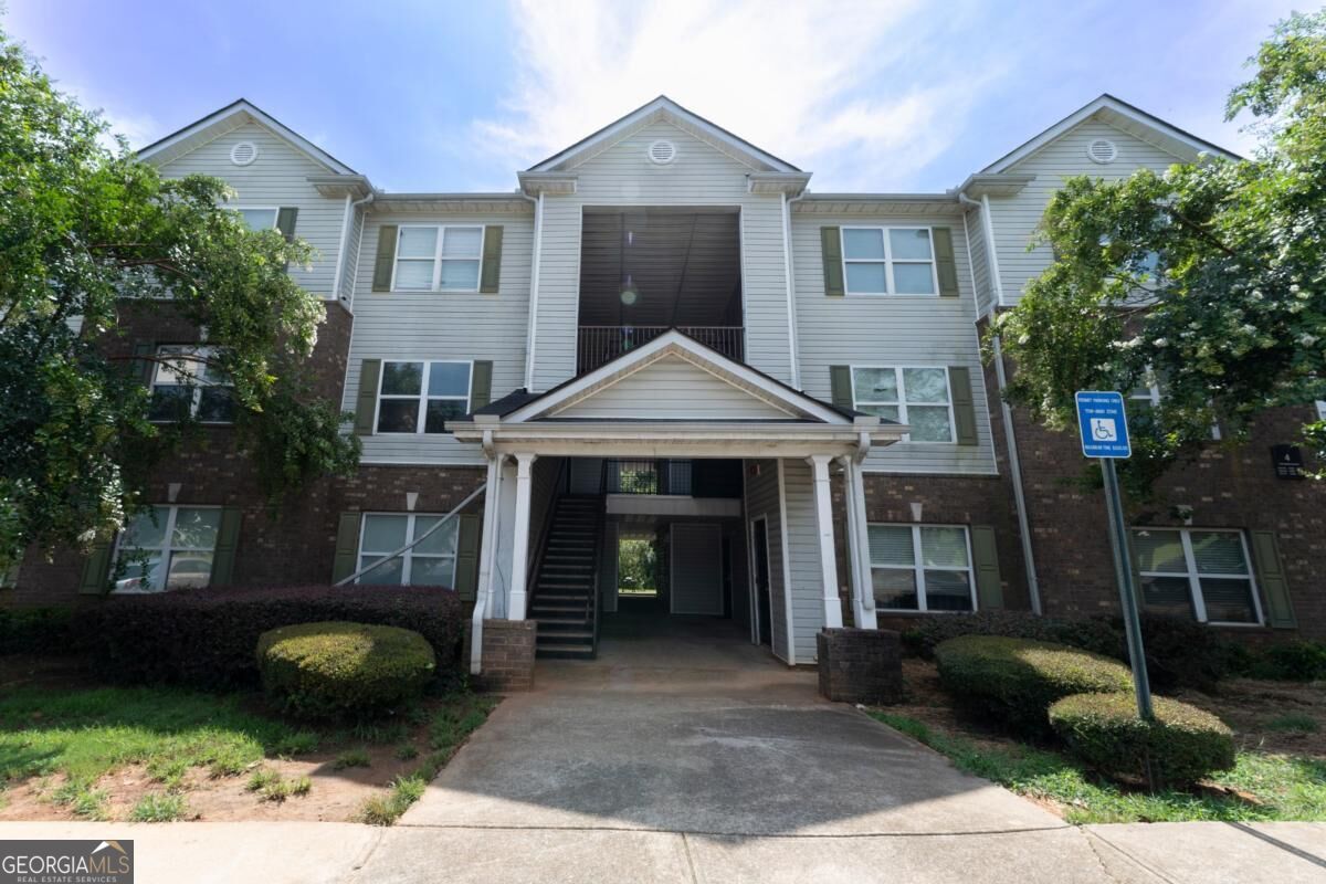 Three-story apartment building with a covered central entrance and brick lower level.