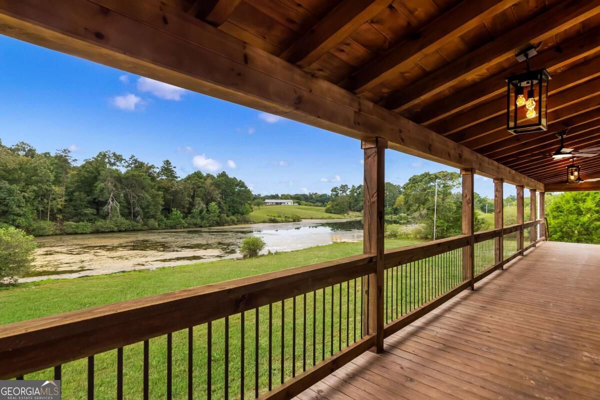Covered wooden deck overlooking a pond and tree-lined fields