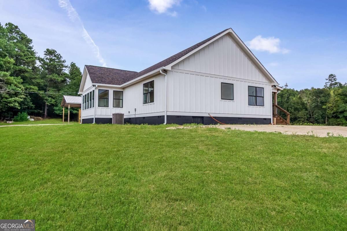 White single-story house with a covered side porch and broad green lawn.