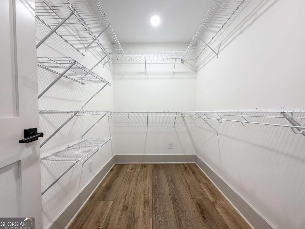 Walk-in closet with white wire shelving on three walls and wood-look plank flooring.