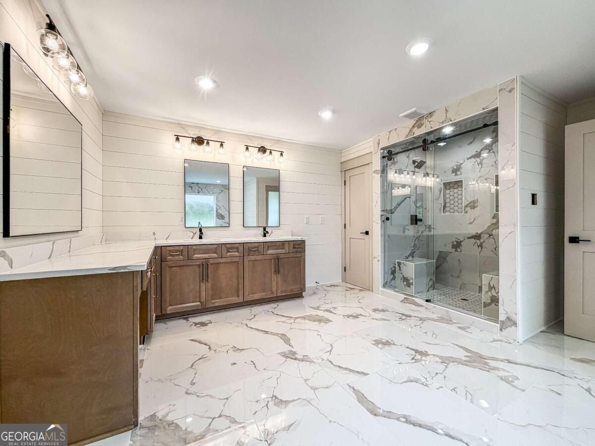 Bathroom with double vanity, dramatic marble-look flooring, and a glass-enclosed walk-in shower.