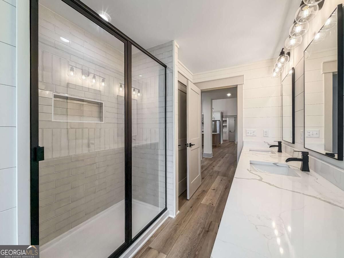 Bathroom with a black-framed glass shower and long double vanity with black faucets.