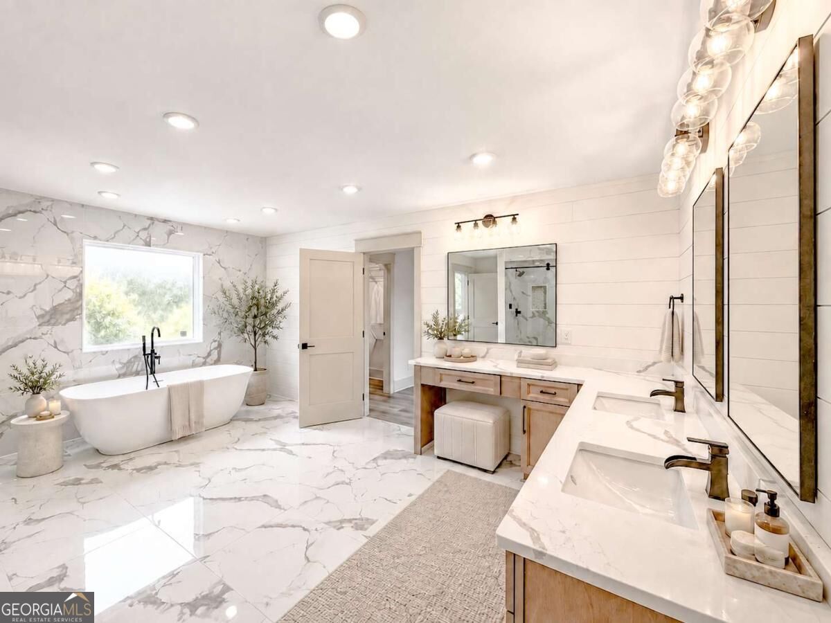 Bright bathroom with a freestanding tub, marble-look tile, and a long double-sink vanity.