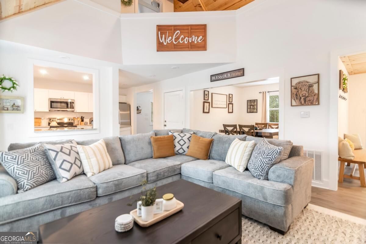 Living room with a gray sectional, dark coffee table, and open view into the kitchen and dining area.