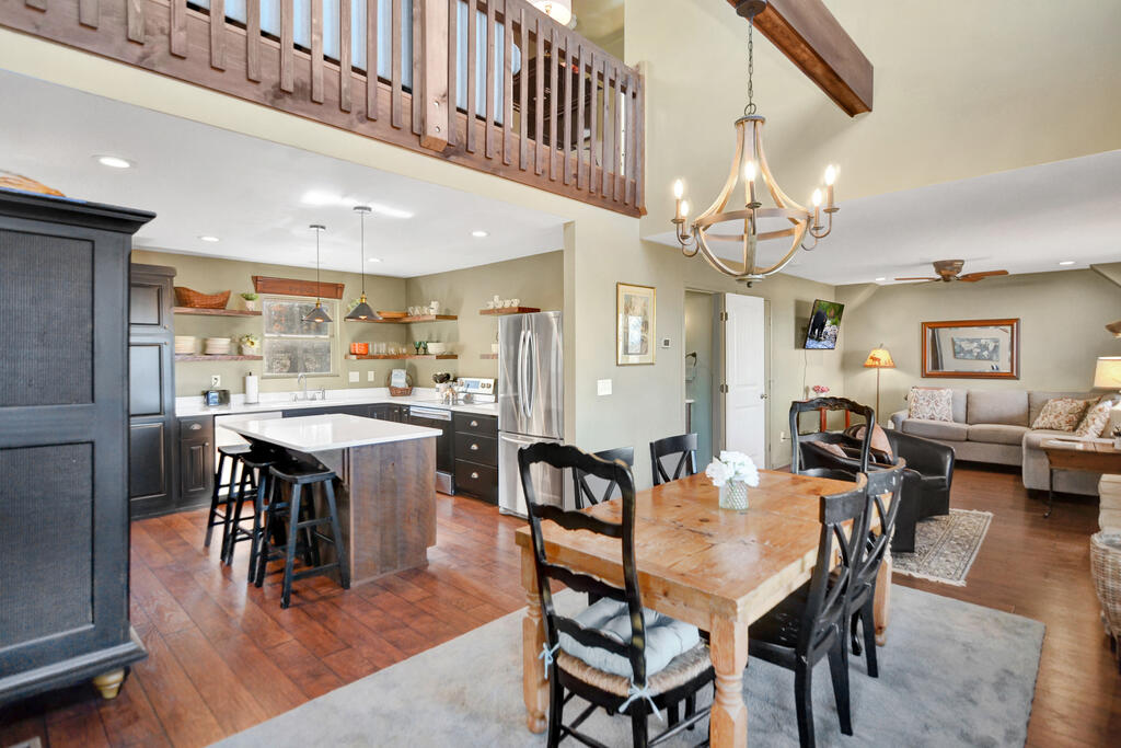 Open-plan kitchen and dining area with a wood island, large table, and loft railing.