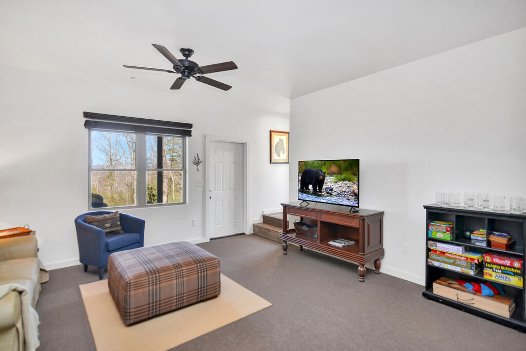 Living room with a blue armchair, plaid ottoman, and window overlooking trees.