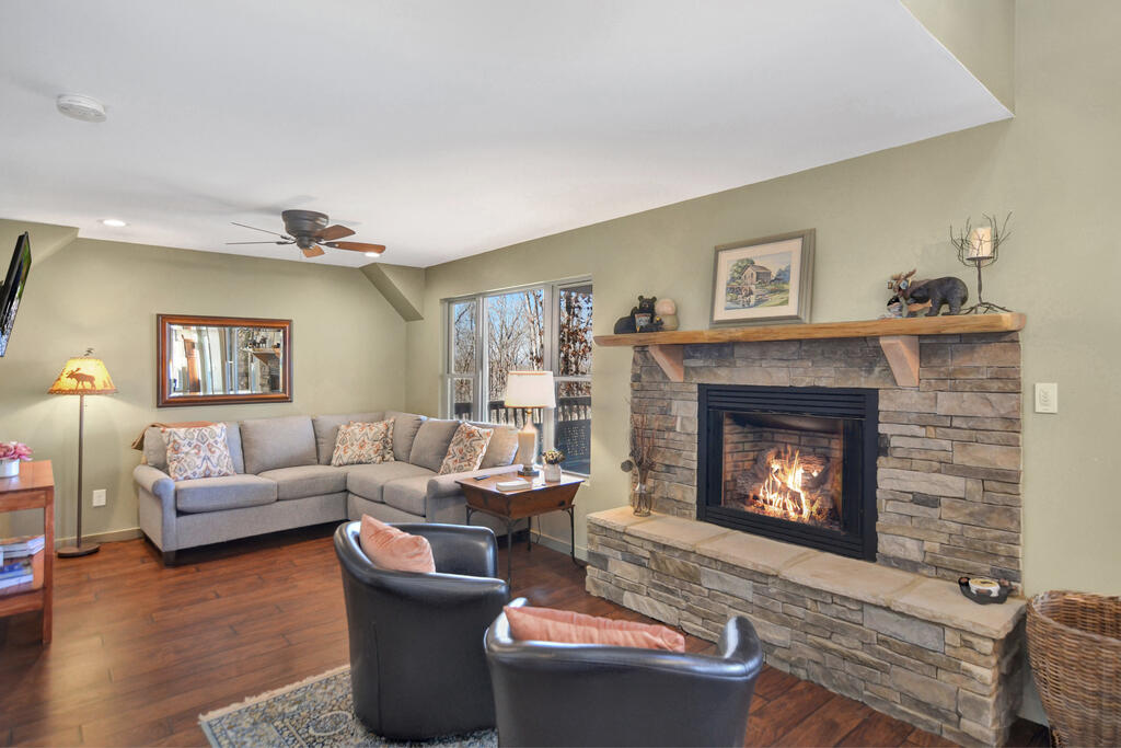 Living room with a stone fireplace, gray sectional sofa, and leather chairs.