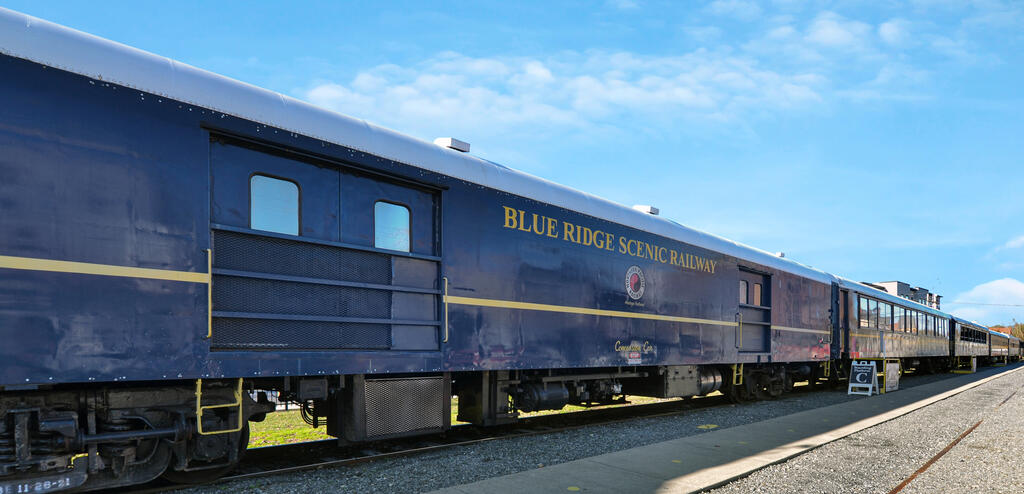 Blue Ridge Scenic Railway passenger train with yellow trim on the tracks.