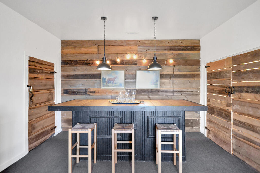 Dining area with a wood-topped island, three stools, and rustic reclaimed-wood walls.