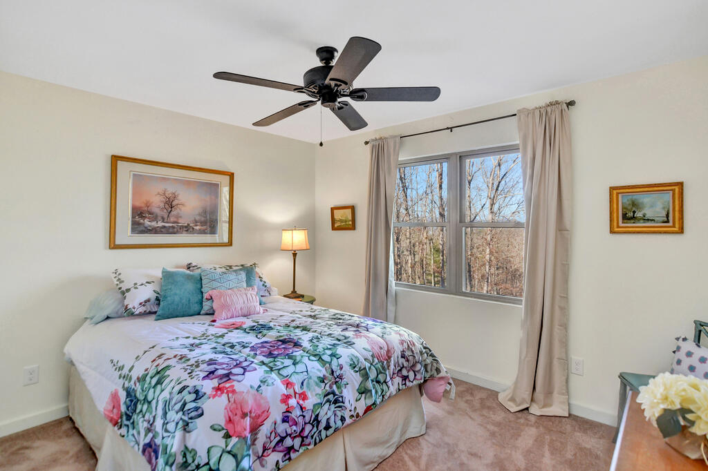 Bedroom with a floral bed and a large window overlooking leafless trees.