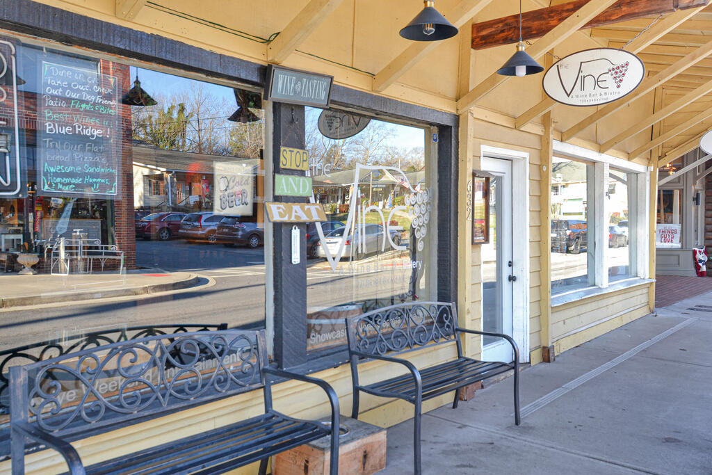 Yellow-sided Blue Ridge storefront with covered sidewalk, metal benches, and The Vine Wine Bar & Bistro sign.