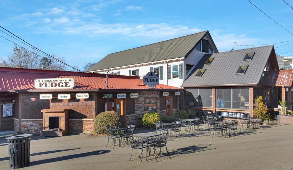 Fudge shop with outdoor seating and signs for fudge, pralines, coffee, and milkshakes.