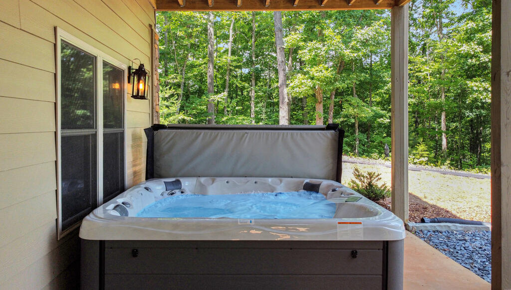 Hot tub on a covered porch overlooking trees.