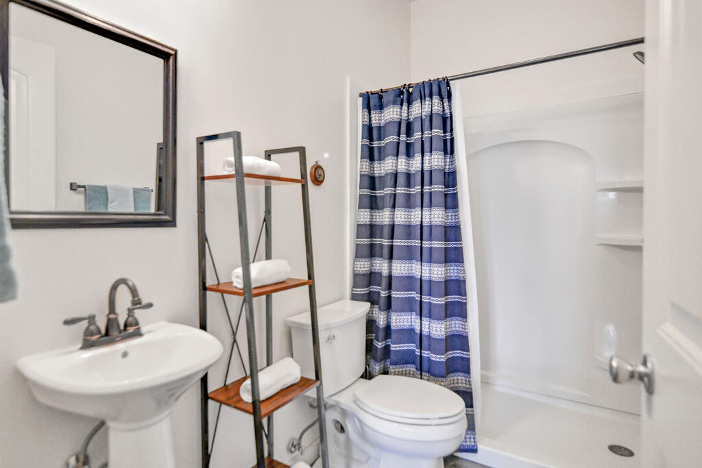 Bathroom with a pedestal sink, toilet, and shower with a blue patterned curtain.