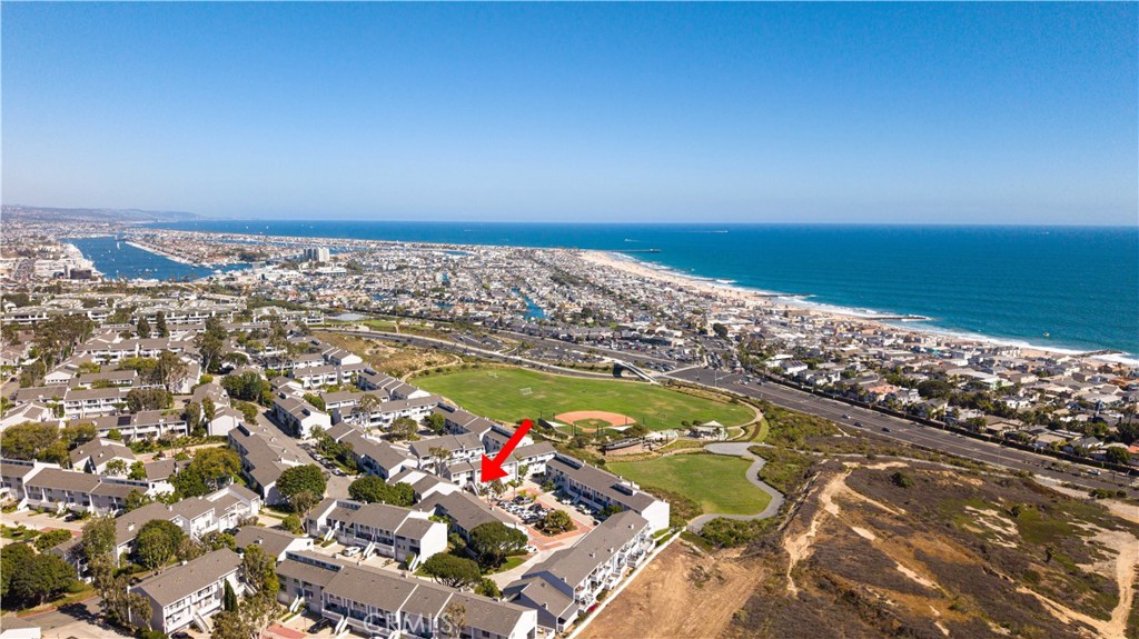 Coastal neighborhood from above, with a red arrow marking a home near the ocean.