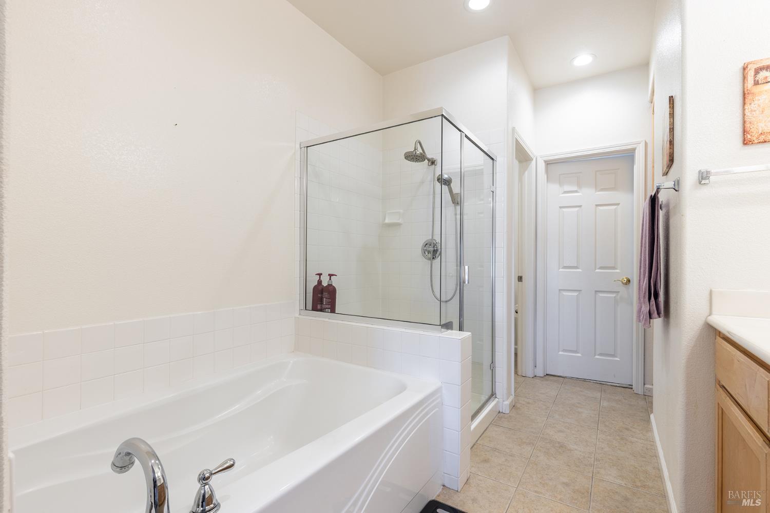Bathroom with a soaking tub, glass-enclosed shower, and tiled floor.