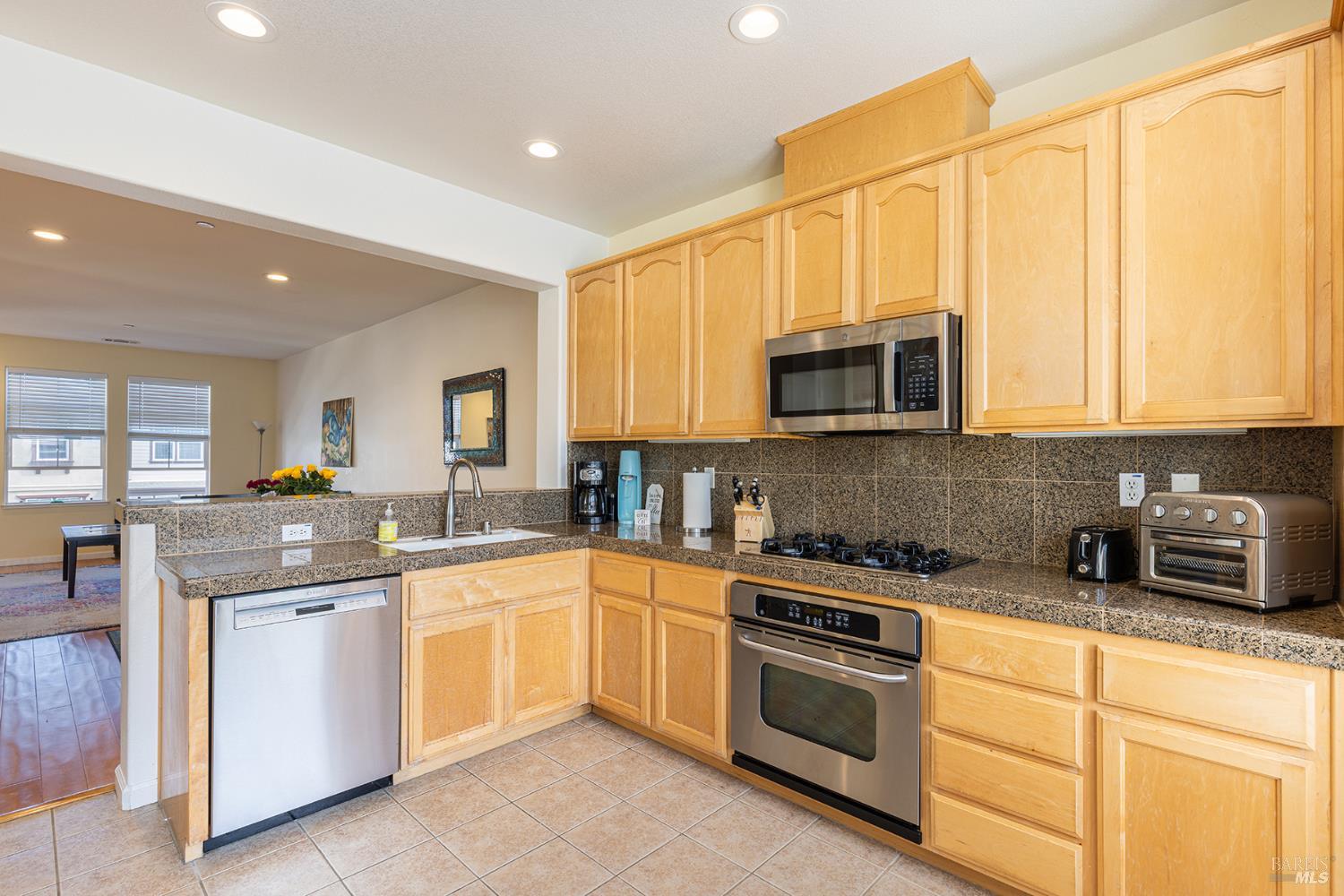 Kitchen with light wood cabinets, granite counters, and stainless steel appliances.
