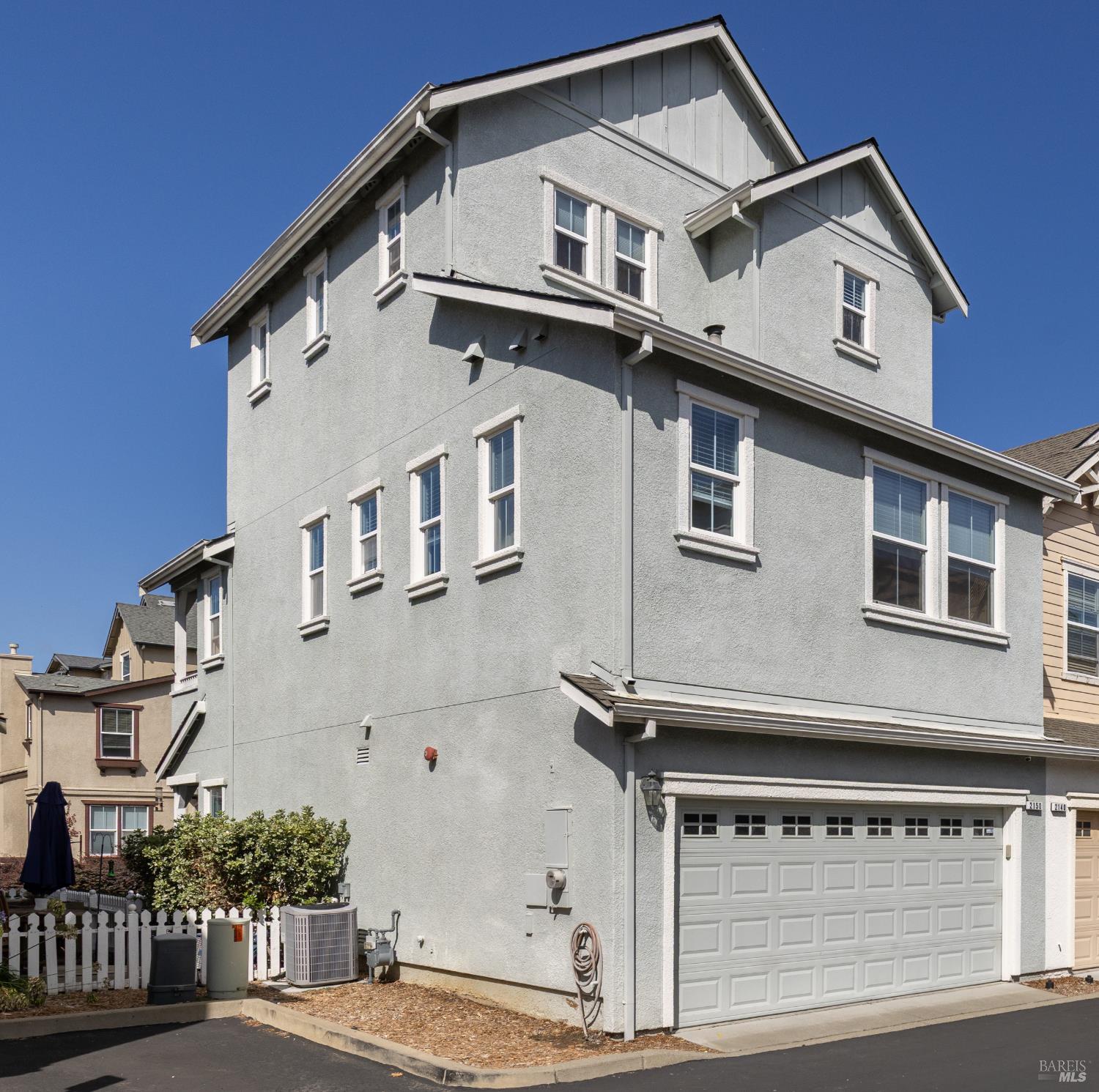 Multi-story gray stucco house with white trim and an attached double garage.