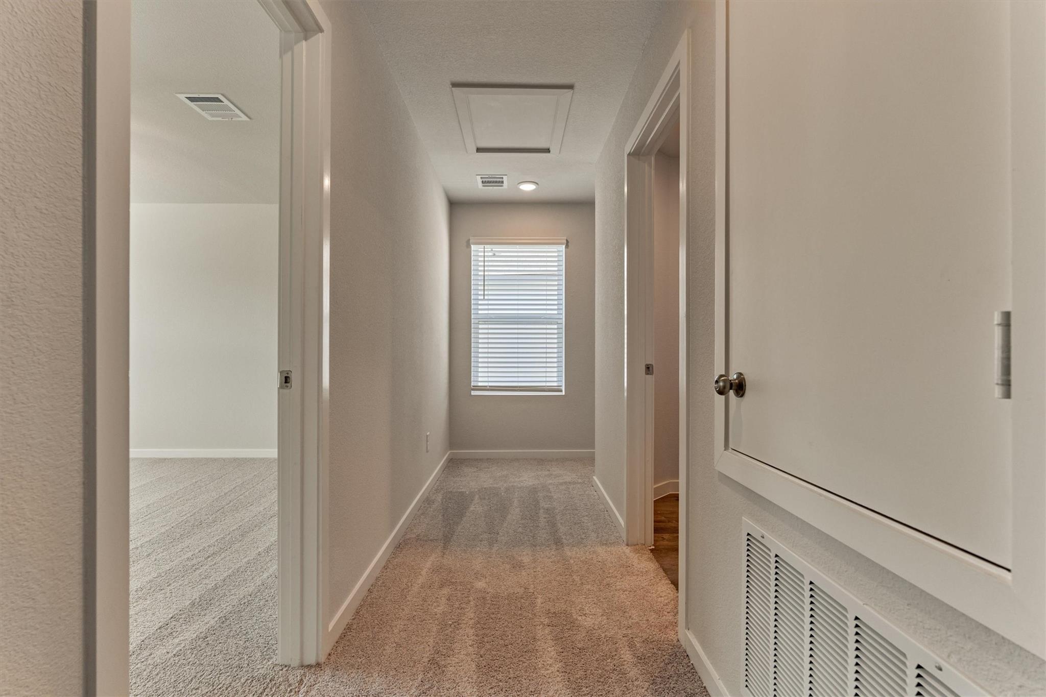 Carpeted hallway with a window at the end and a large white utility cabinet.