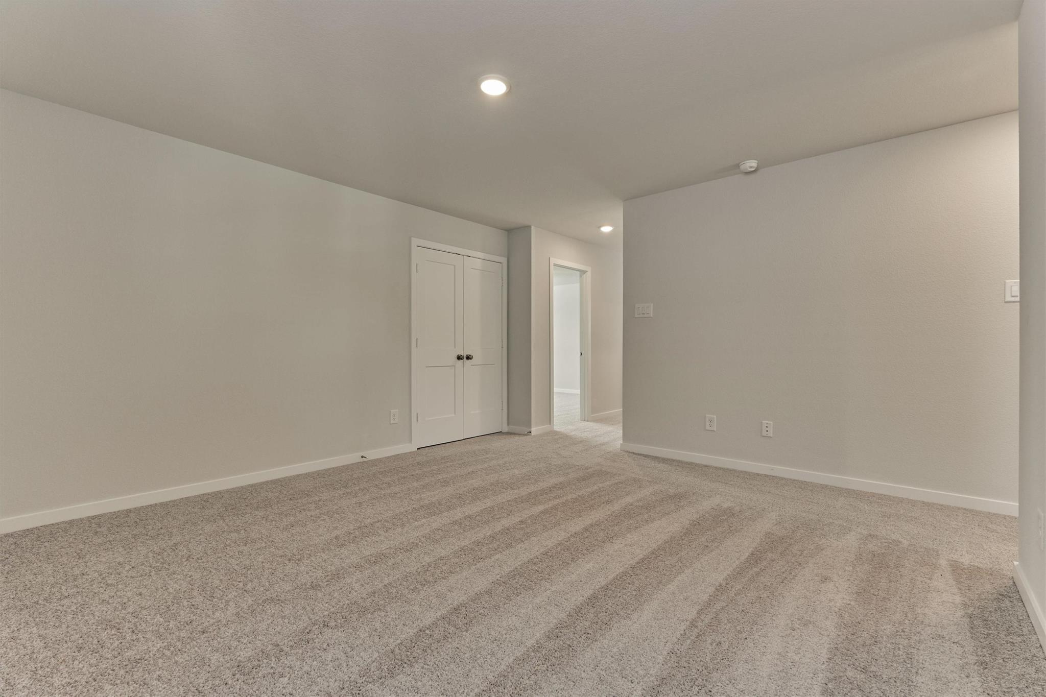 Empty carpeted room with a double-door closet and doorway to the hall.