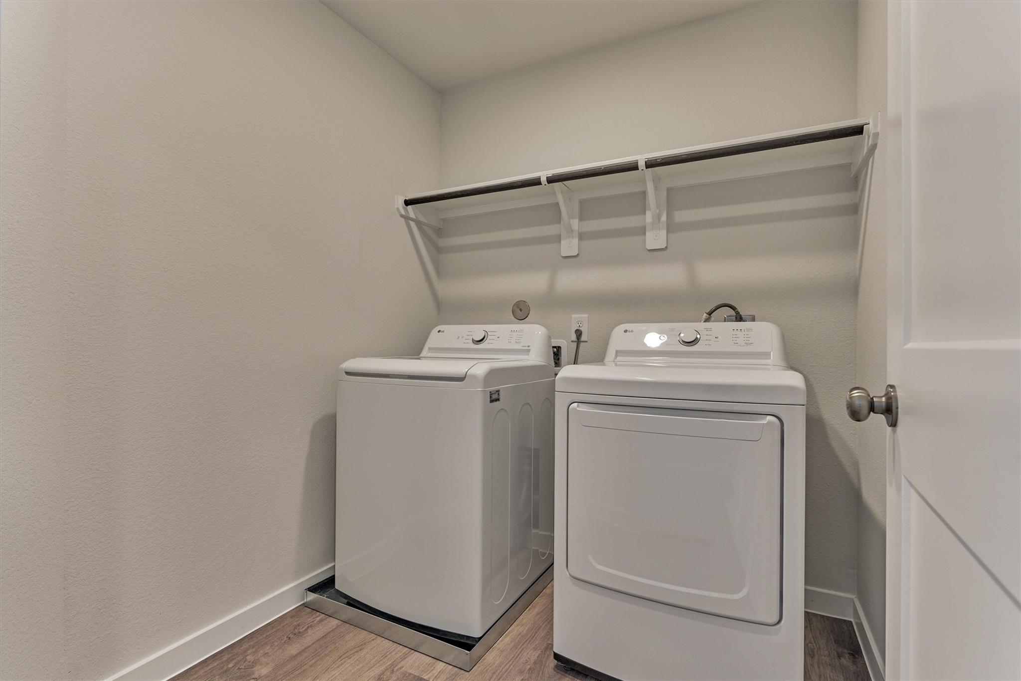 Laundry room with a washer and dryer beneath an overhead storage shelf.