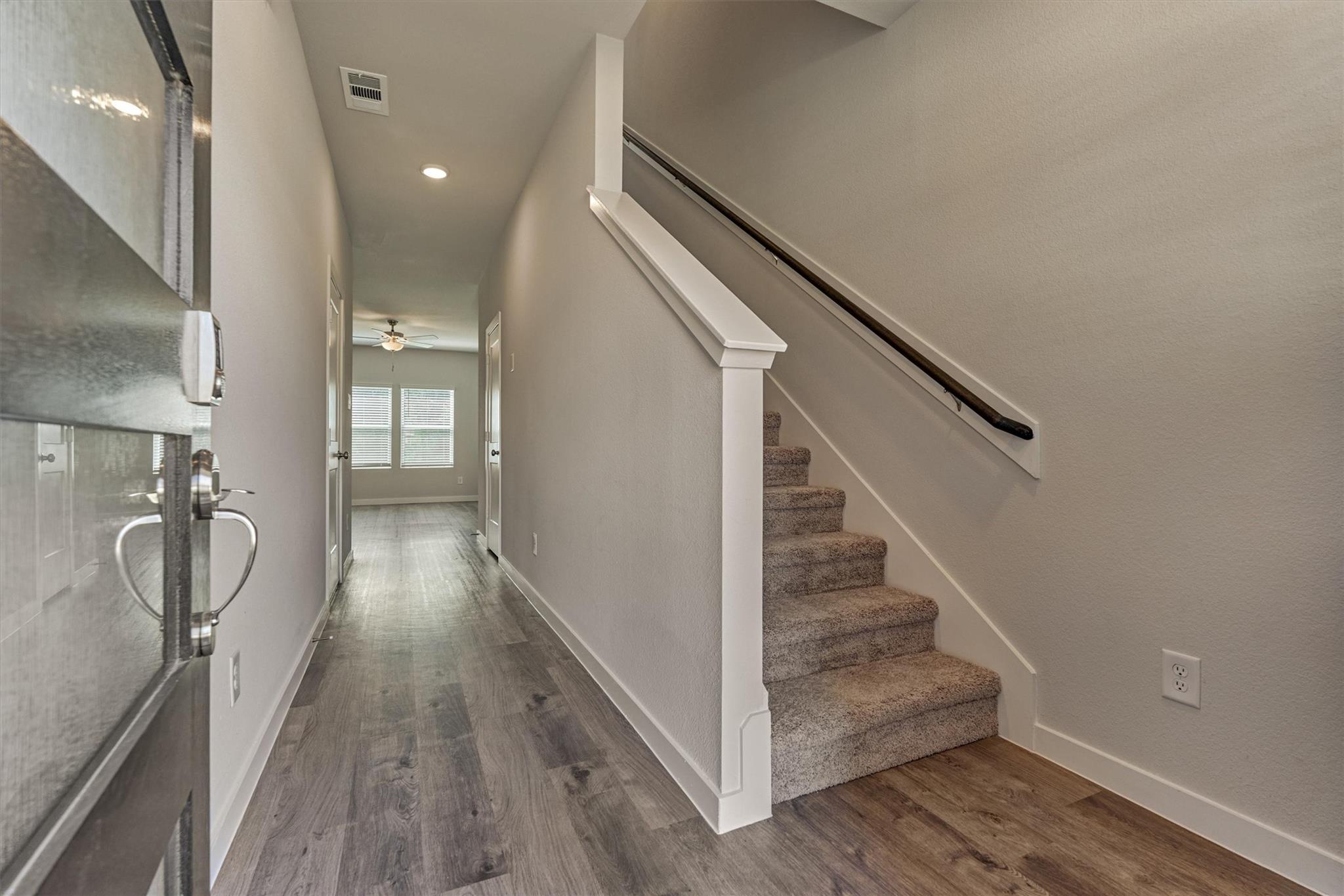 Entry hall with gray wood-look floors, a carpeted staircase, and a glazed front door.