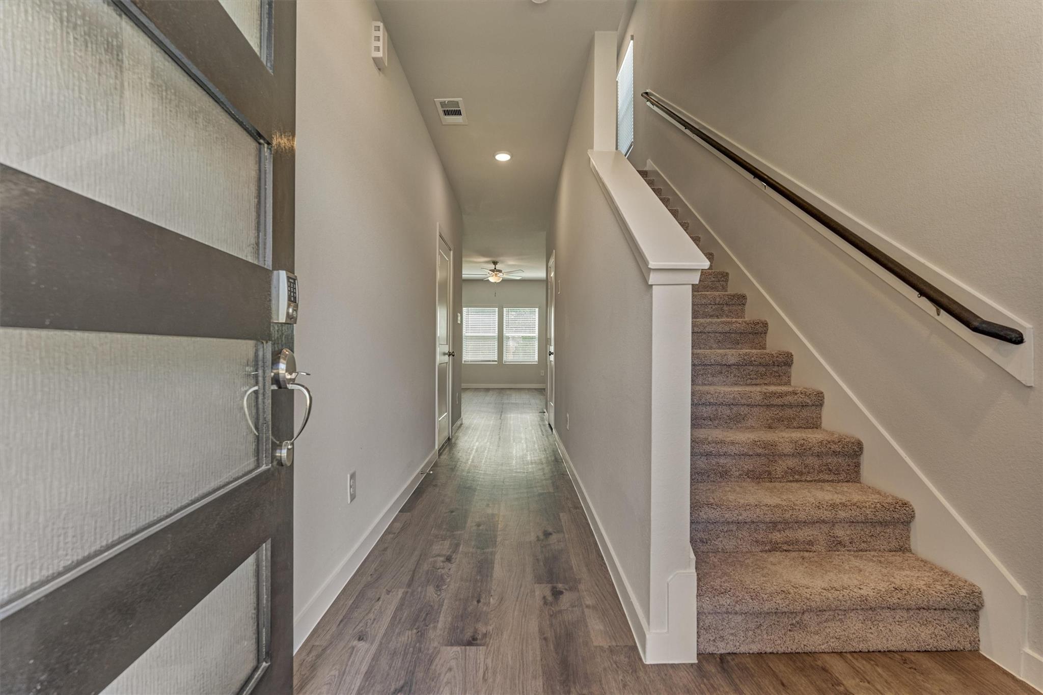 Entry hall with wood-look flooring and a carpeted staircase beside the front door.