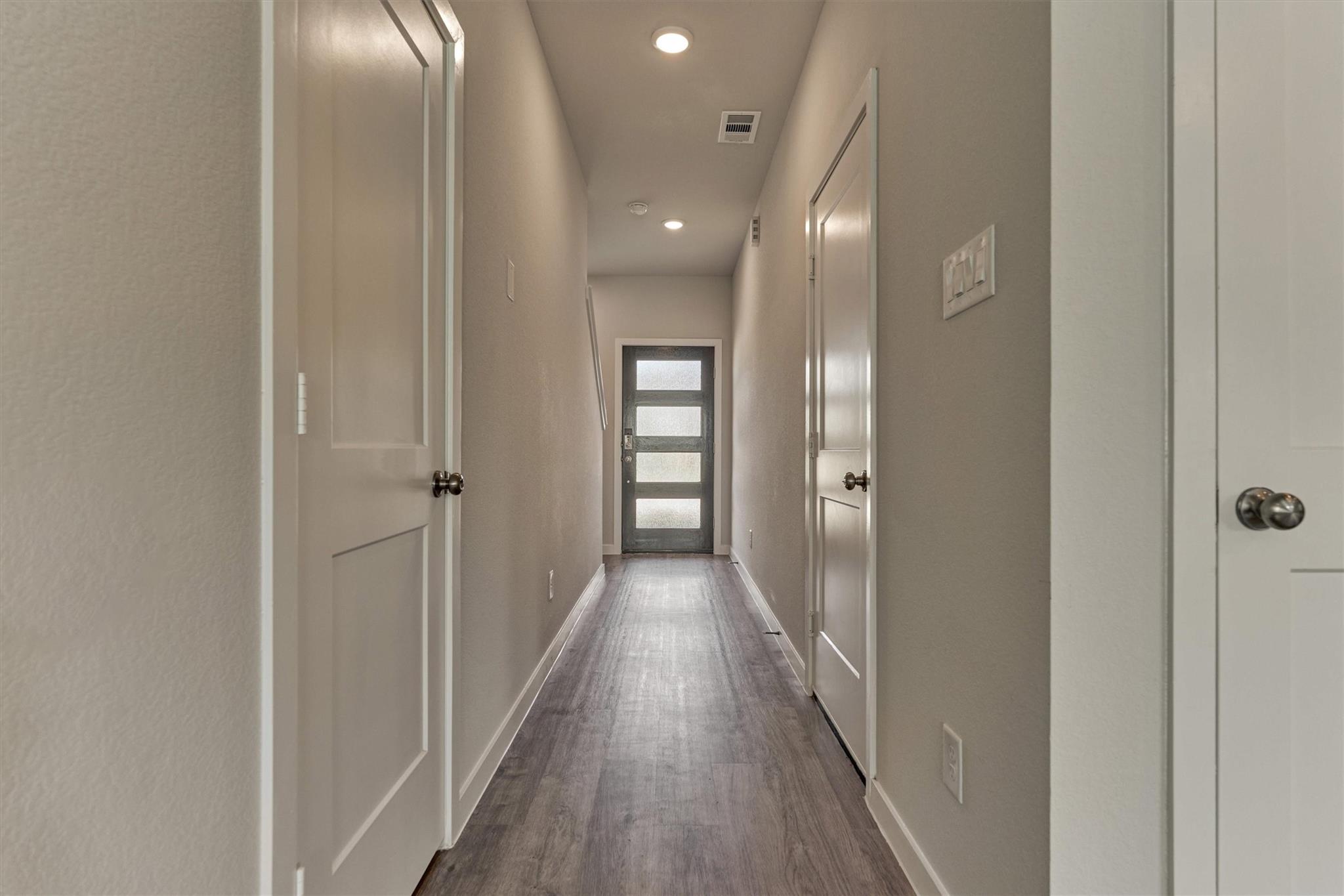Entry hallway with gray flooring and a dark front door with four frosted glass panels.