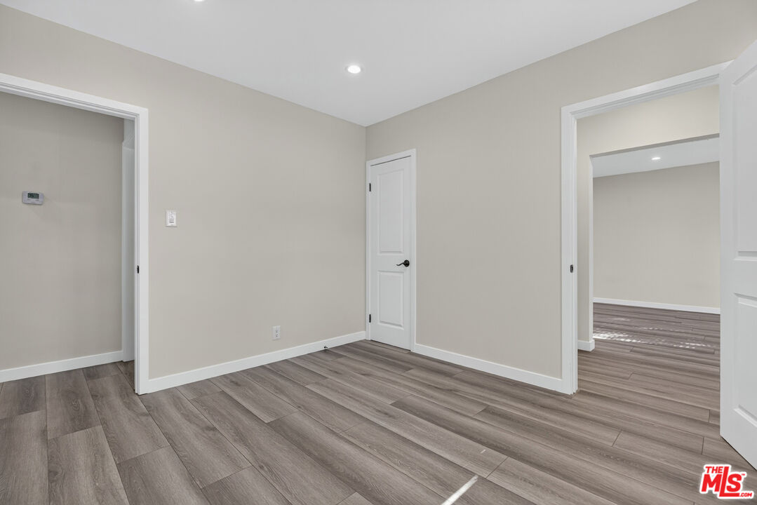 Empty room with gray-brown plank flooring, neutral walls, and doorways to adjoining rooms.