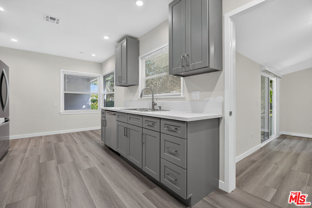 Kitchen with gray cabinets, white countertops, and gray wood-look floors.
