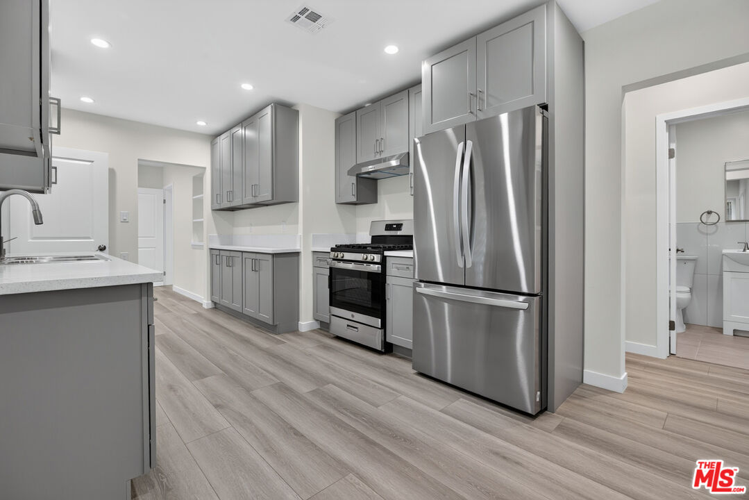 Kitchen with gray cabinets, stainless steel appliances, and wide-plank flooring.