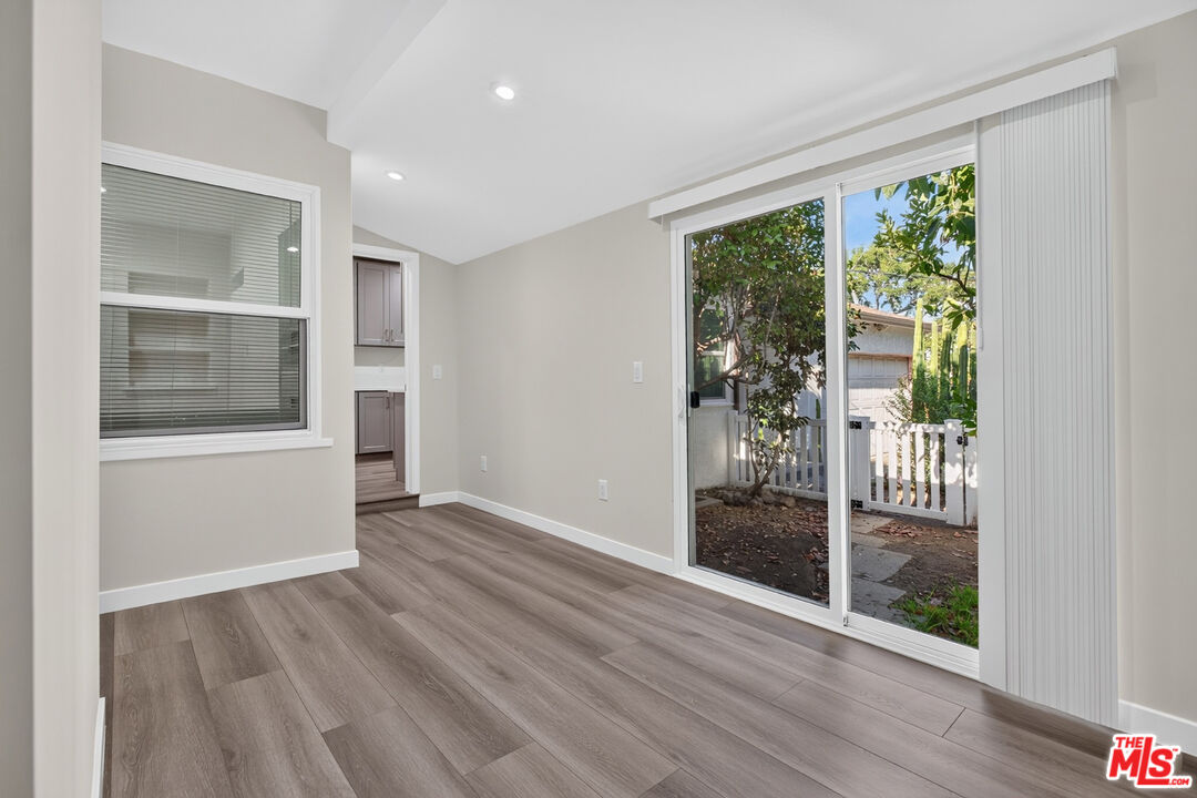 Empty room with gray wood-look floors and sliding glass doors opening to a fenced yard.