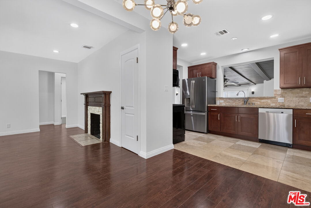 Open kitchen and living area with dark wood cabinets, stainless appliances, and a tiled fireplace.