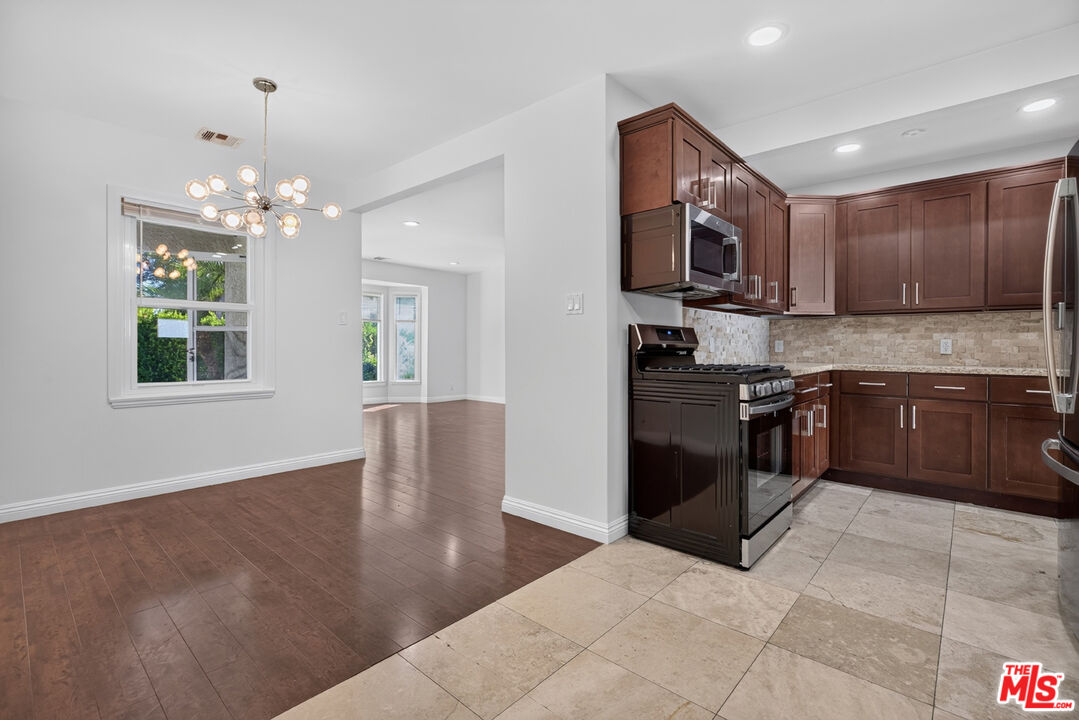 Kitchen and dining area with dark wood cabinets, stainless steel appliances, and adjoining wood-floored space.