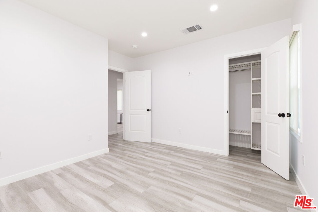 Vacant bedroom with light gray flooring, an open closet, and a tall window.