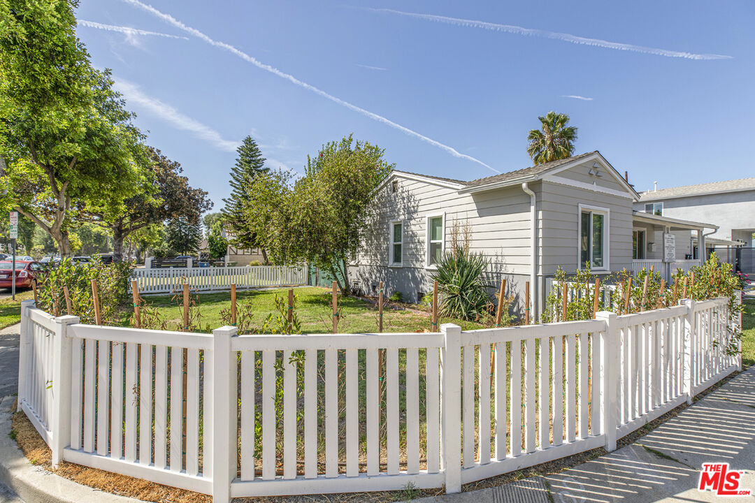 Single-story home with light siding, a white picket fence, and a landscaped front yard.