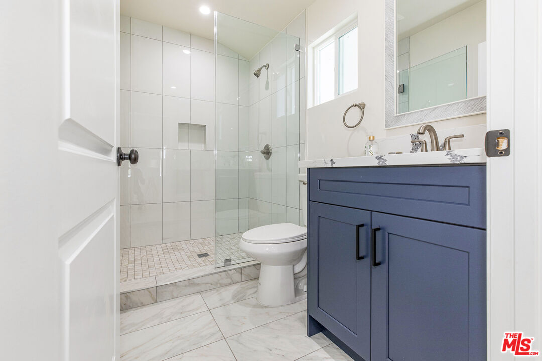 Bathroom with a glass walk-in shower and navy blue vanity.