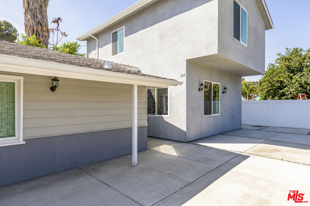 Two-story stucco house with an attached garage and broad concrete driveway.