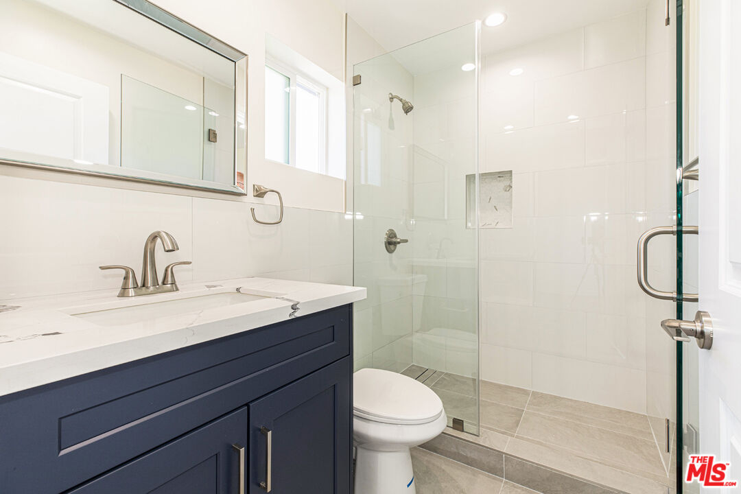 Bathroom with a navy vanity and glass-enclosed white-tile shower.