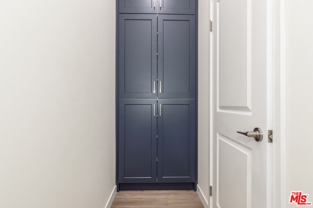Closet with tall navy-blue built-in cabinets, silver handles, and an open white door.