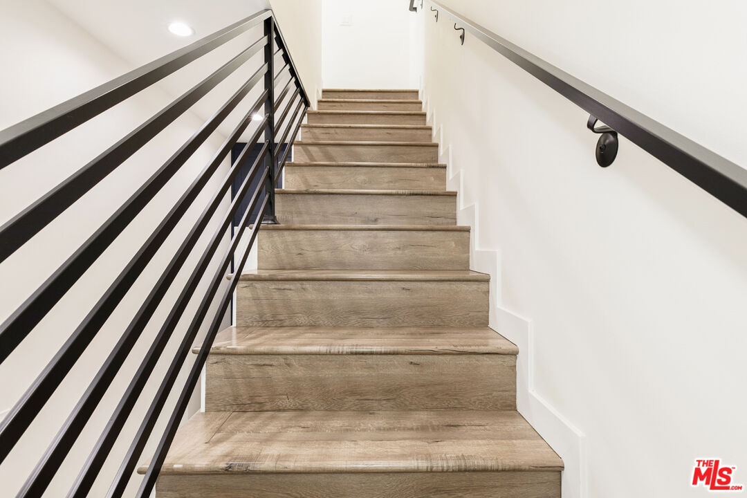 Wood staircase with black metal railings and white walls.