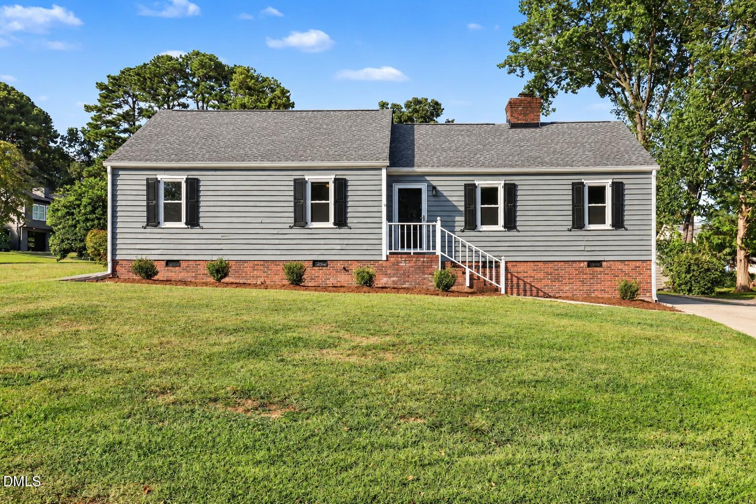 Gray single-story home with black shutters, brick foundation, and white front steps.