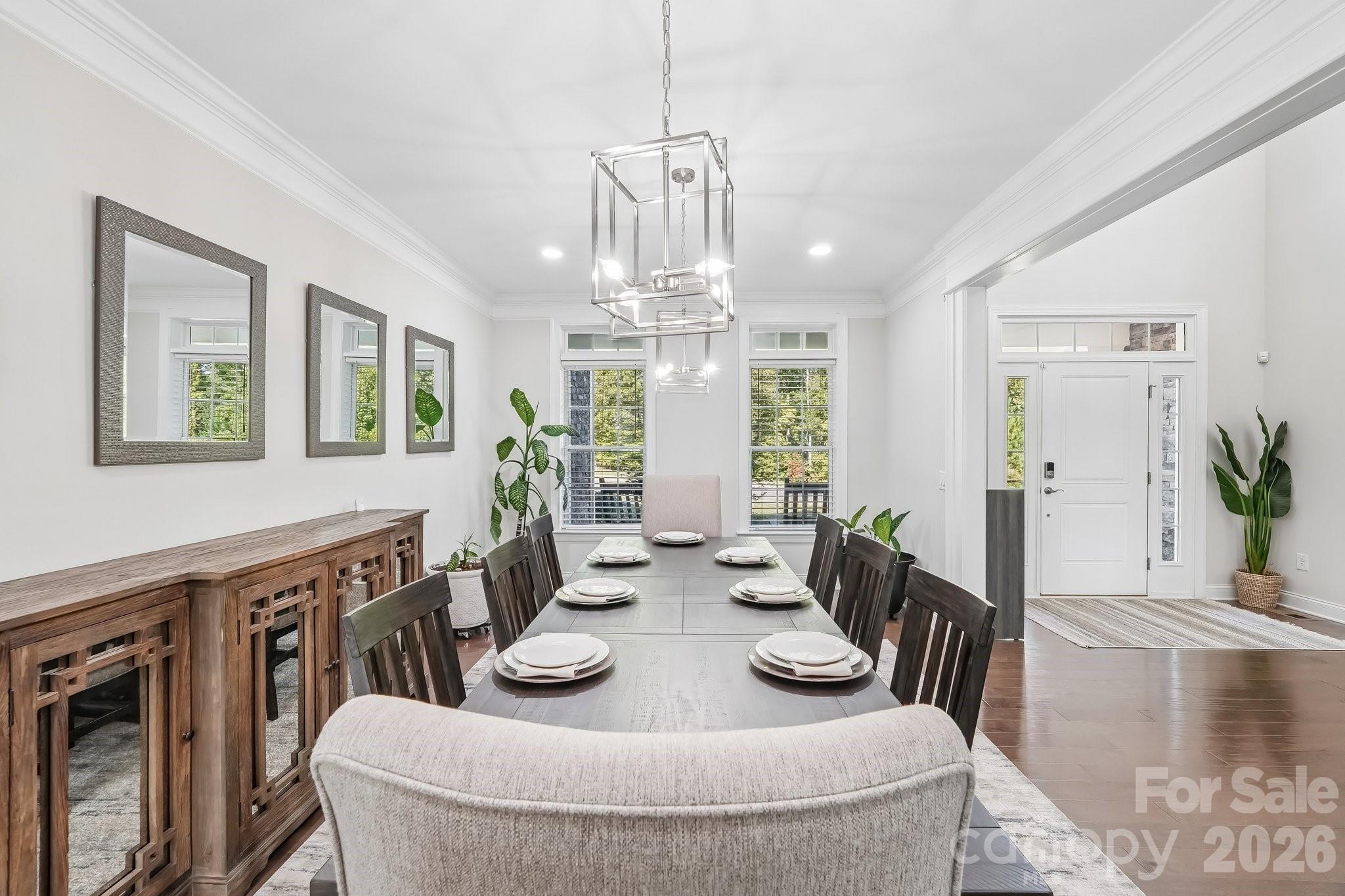 Staged dining room with a long set table, wooden buffet, and front entry.