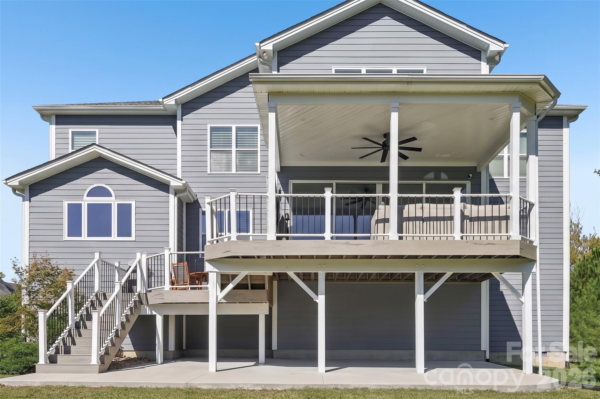 Rear of a gray two-story home with a large covered deck and exterior staircase.
