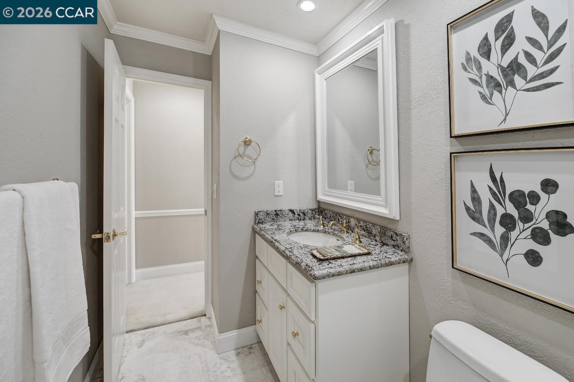 Bathroom with a white vanity, granite countertop, marble-look floor, and framed botanical prints.