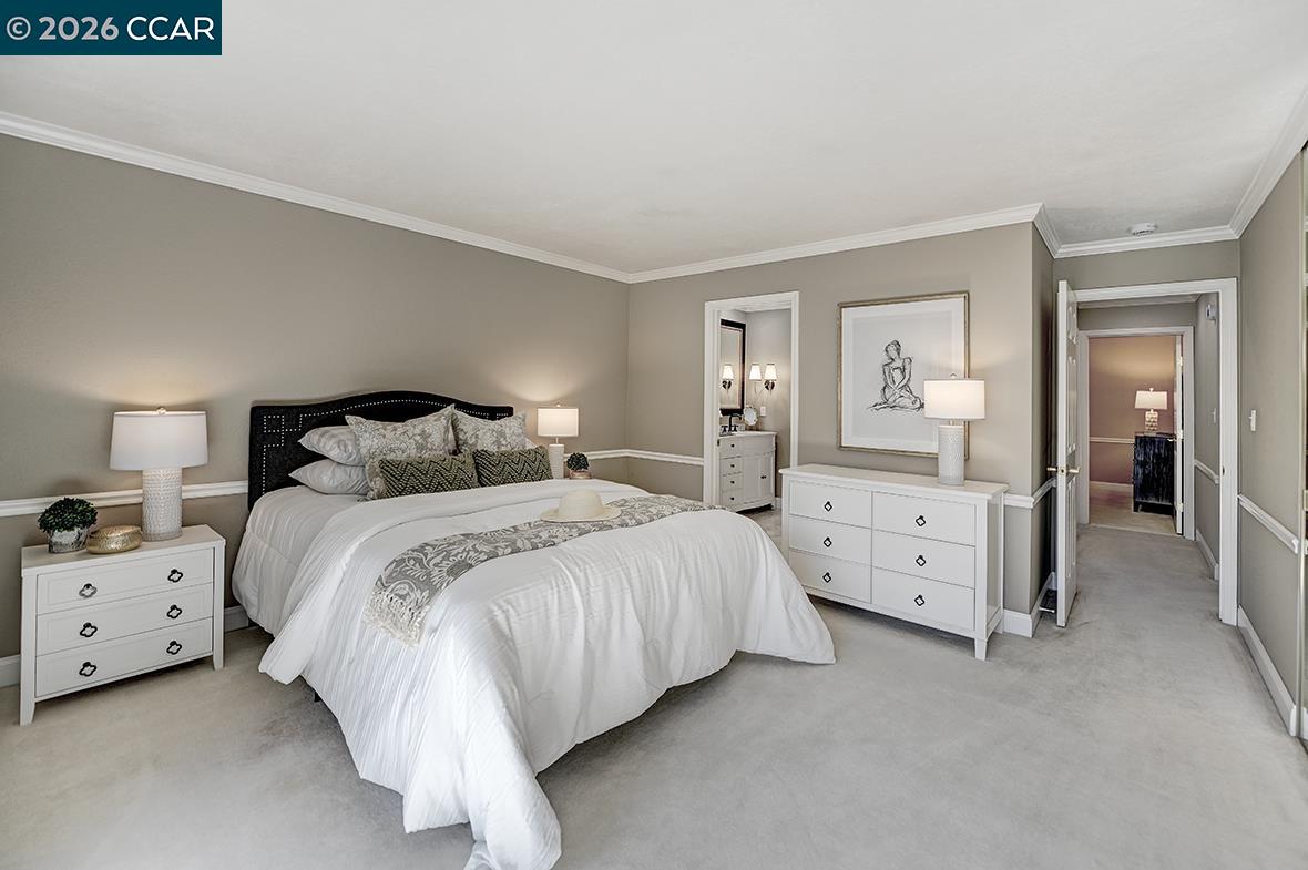 Staged bedroom with a large white bed, matching dressers, and gray walls with white wainscoting.