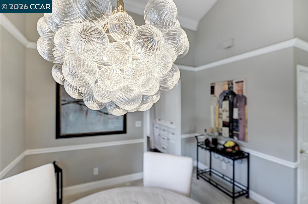 Dining area with a sculptural glass-globe chandelier, round table, and white chairs.