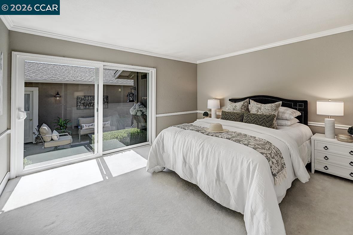 Staged bedroom with a white bed and sliding glass doors overlooking a patio.
